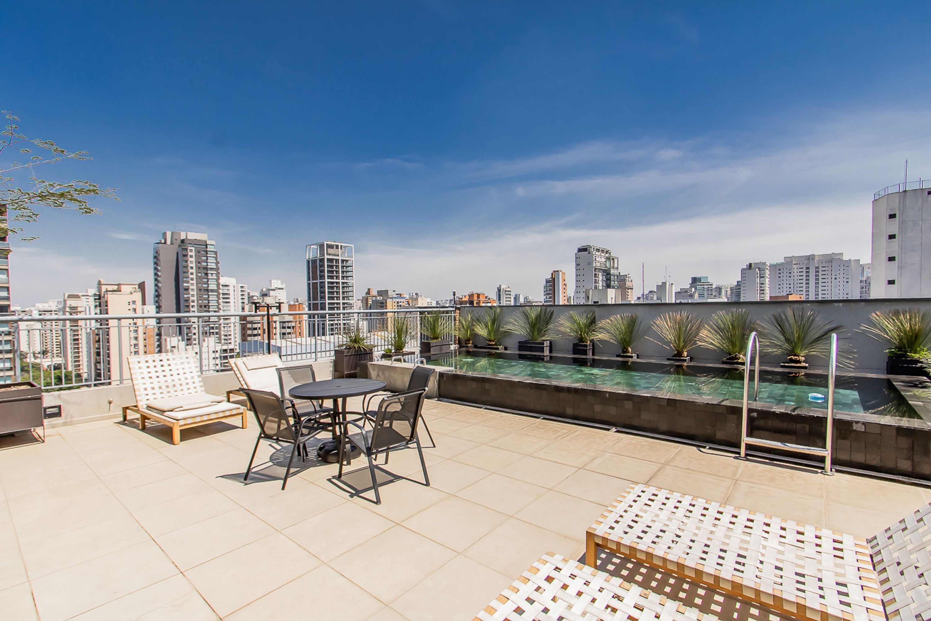 Terraza en la azotea con piscina, zona de estar y vistas al horizonte urbano.