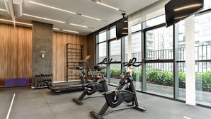 Een moderne sportschool met trainingsapparatuur, grote ramen en stadszicht.