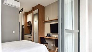 Een moderne hotelkamer met een bed, een bureau, een stoel en een kitchenette.