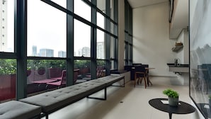 Een modern interieur met grote ramen, een zithoek, een kleine tafel met een plant en een keukenhoek.