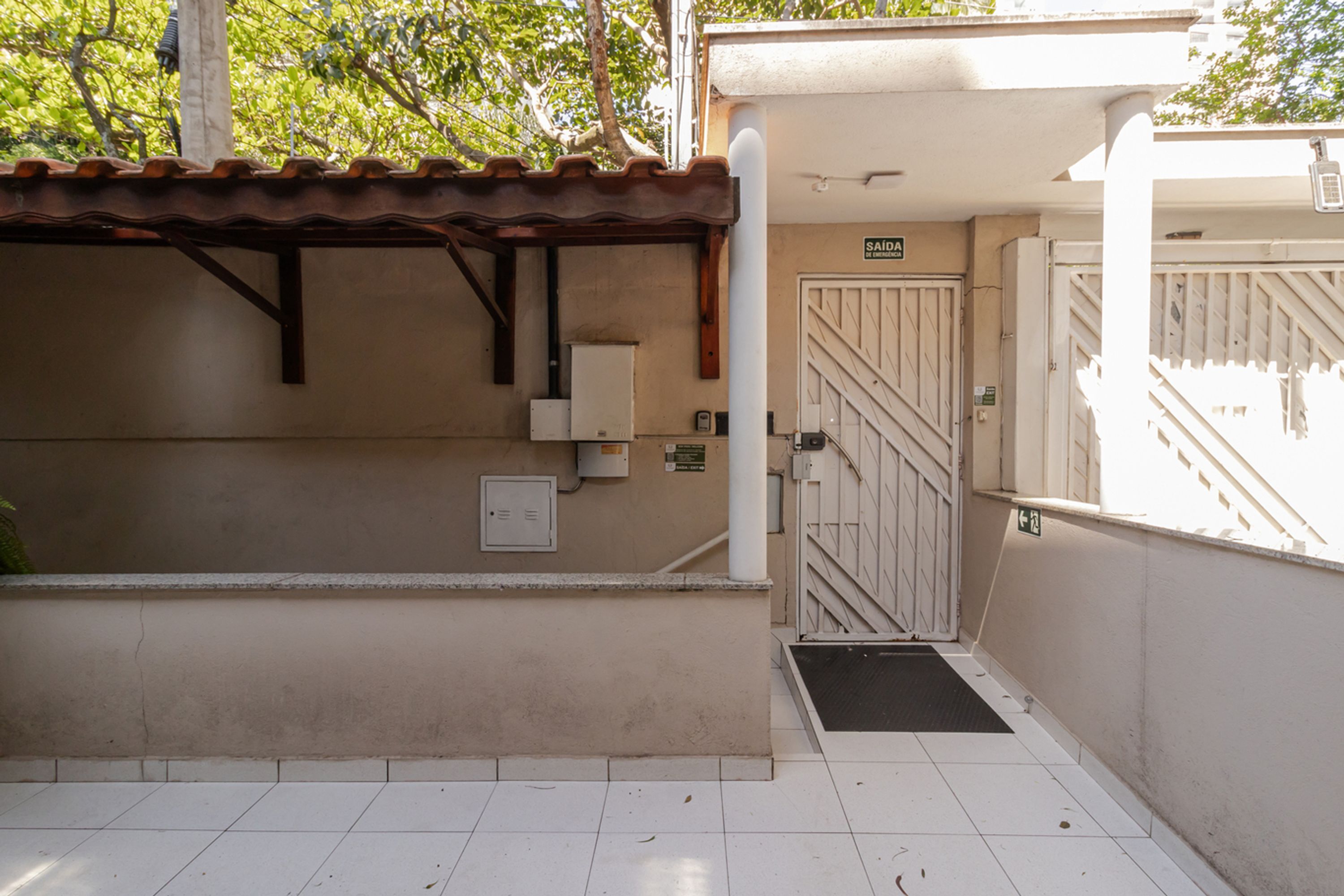 A building entrance with a tiled floor, a metal gate, and a sign indicating a restroom.