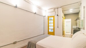 Un dormitorio con cama, puerta y un pequeño baño.