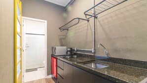 Una cocina compacta con encimera de granito, pileta de acero inoxidable y microondas integrado.