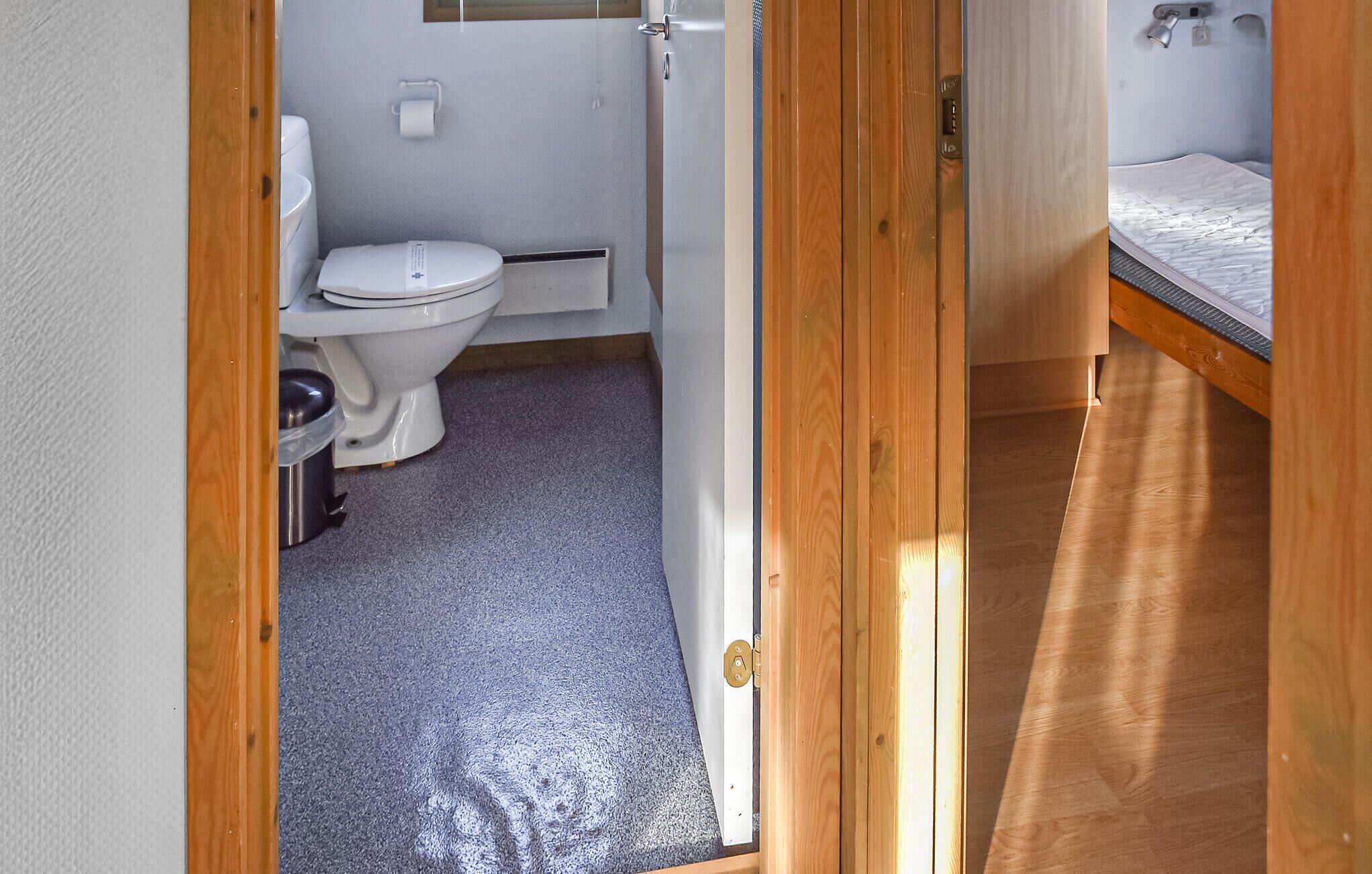 Un bagno compatto con il water, un cestino e una zona doccia.