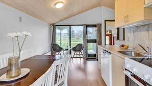A modern kitchen with a wooden ceiling, a dining area with two chairs, and a view of the outdoors through large windows. - Gorgeous home in Hanstholm with swimming pool (Hanstholm)
