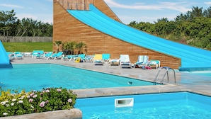 Ein Swimmingpool mit einer Holzrutsche und Liegestühlen.