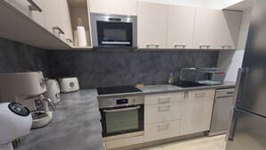 Una cocina moderna equipada con horno integrado, microondas, cafetera y lavavajillas.