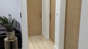 Un pasillo con puertas de madera, una planta en maceta y una pequeña mesa redonda.