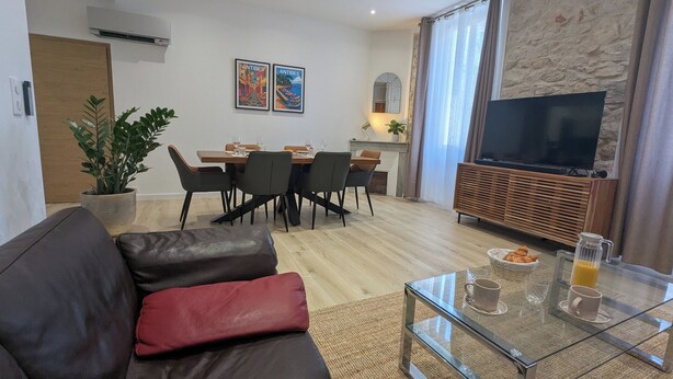 Una sala de estar moderna con un sofá de cuero, una mesa de centro de vidrio y un comedor con una mesa y sillas de madera.