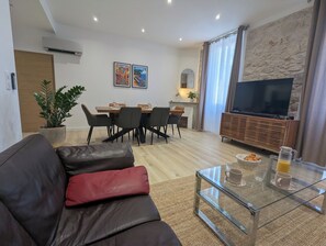 A modern living room with a leather sofa, a glass coffee table, and a dining area with a wooden table and chairs. - Le Gazan - Newly spacious apt for 2 close to Vieil Antibes (Antibes)