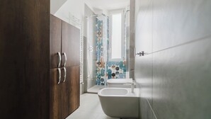 A modern bathroom with a wooden cabinet, a white sink, and a toilet with a blue patterned shower curtain. - La Boutique Apartment - Borgo Delle Colonne (Parma)