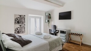A bedroom with a bed, a desk, a chair, a TV, and a window with curtains. - La Boutique Apartment - Borgo Delle Colonne (Parma)