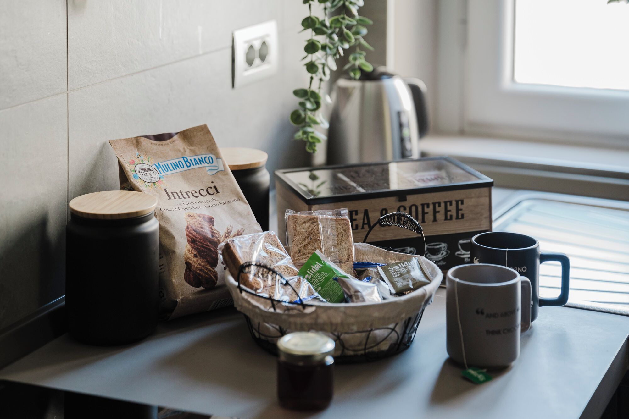 Een tafel met een koffiezetapparaat, een zak koffie, een doos met de tekst 'COFFEE' en twee mokken.
