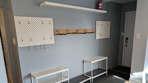 En hall med två vita metallbänkar, en vit hylla ovanför och en brandsläckare på en vit hylla.