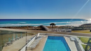 A pool area with lounge chairs and a view of the ocean. - Regency Towers #401 East - Sea La Vie (Pensacola Beach)