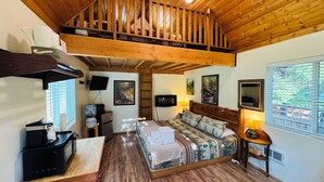A cozy room with a loft bed, wooden ceiling, and a TV mounted on the wall.