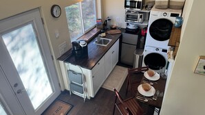 Eine kompakte Küche mit Spüle, Mikrowelle, Toaster und kleinem Kühlschrank.