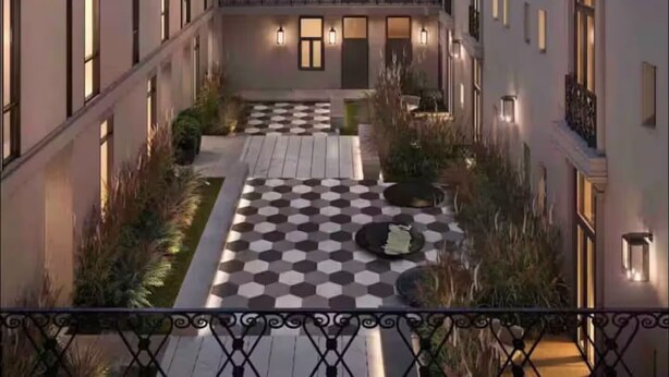 En modern byggnad med en innergård som har ett rutmönstrat golv och som omges av balkonger och fönster.