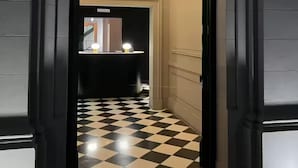 En hall med ett rutmönstrat golv som leder till ett rum med ett handfat och en spegel.