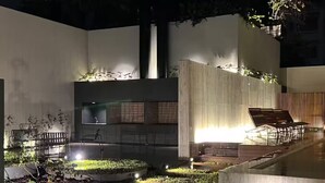 Un espace extérieur moderne doté d’une piscine, de coins salon et d’un élément décoratif aquatique.