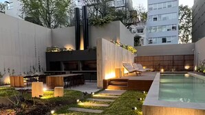 Un espace piscine extérieur moderne, doté d’une terrasse en bois, de chaises longues et d’un coin repas.
