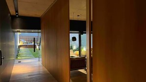 Un intérieur moderne avec un plancher en bois et des portes coulissantes donnant sur un balcon avec vue sur un jardin et une piscine.