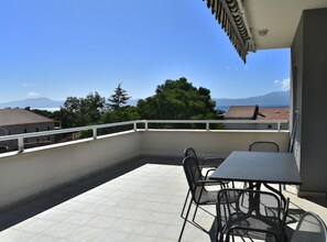 Un balcon avec un sol carrelé, une table et des chaises.
