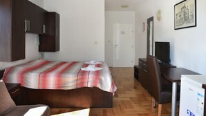 Une chambre d’hôtel équipée d’un lit, d’un bureau, d’une chaise, d’une télévision et d’un réfrigérateur.