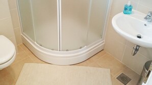 Une salle de bain avec une douche à parois de verre, un lavabo blanc et des toilettes.