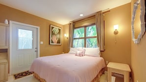 A bedroom with a bed, a bedside table, a door, a window with curtains, and a wall-mounted light fixture. - Explore Dtwn Sarasota & Beaches: Home w/ Lush Yard (Sarasota)