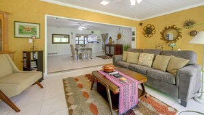 A living room with a sofa, armchair, coffee table, and a dining area in the background. - Explore Dtwn Sarasota & Beaches: Home w/ Lush Yard (Sarasota)