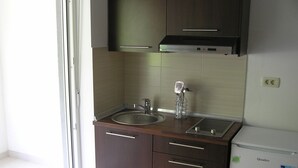 Eine kleine Küchenzeile mit Spüle, zwei Schubladen, einem Herd und einem kleinen Kühlschrank.