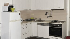 Una cocina moderna con armarios blancos, horno empotrado, microondas y fregadero.