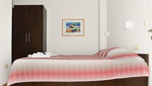Un dormitorio con cama, armario, un cuadro en la pared y una mesita de noche con lámpara.