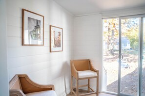 A room with white paneled walls, a wooden chair, and two framed pictures. - Beautifully Renovated 4 Bedroom Home; Fully Furnished & Move-in Ready. (Petersburg)