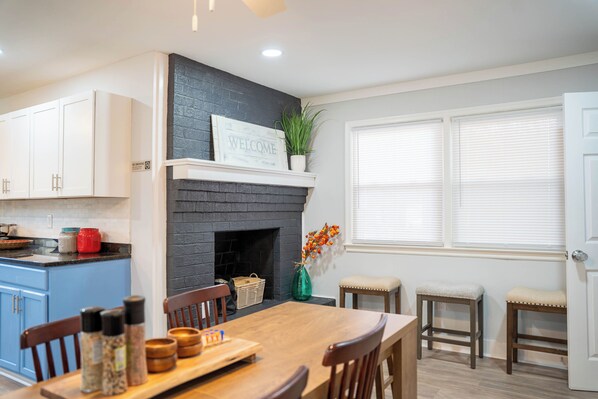 A modern kitchen with white cabinets, a black brick fireplace, and a welcome sign. - Beautifully Renovated 4 Bedroom Home; Fully Furnished & Move-in Ready. (Petersburg)