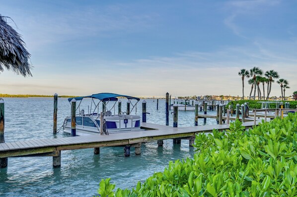 A dock with a boat, a pier, and a view of a distant cityscape. - Riverside Marco Island Condo: Pool & Marina Access (Marco Island)