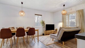 En moderne stue med spiseplads, trægulv og et fladskærms-tv.