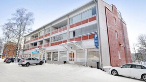 Um edifício com vários andares e uma área de estacionamento na frente.