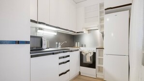 Cozinha moderna com armários brancos, micro-ondas, pia e geladeira.