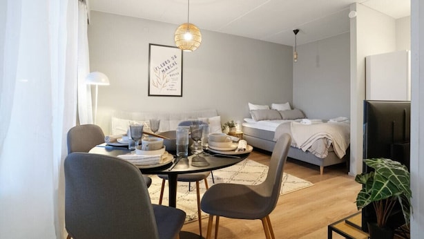 Uma sala de estar moderna e bem iluminada, com área de jantar, sofá e cama.