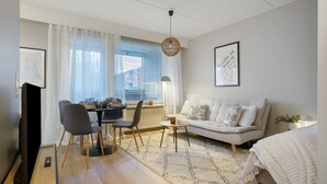 Uma sala de estar moderna com sofá, mesa de jantar, cadeiras e televisão.