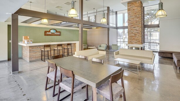 A spacious lobby with a reception desk, seating area, and a large table. - Steps to CSULB: Cozy Condo w/ Pool Access! (Long Beach)