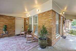 A covered patio area with a brick wall, a door, a window, a table with chairs, and a potted plant. - < 1 Mi to Dtwn Texarkana: Couple's Retreat w/ Yard (Texarkana)