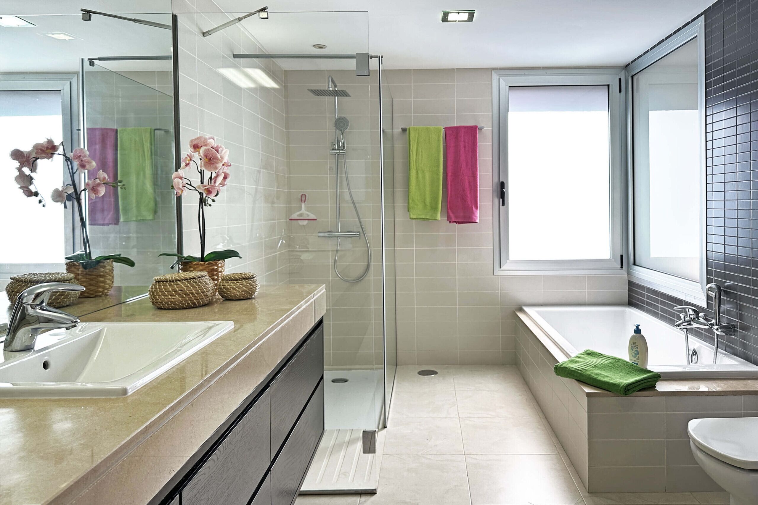 A modern bathroom with a glass-enclosed shower, a large bathtub, and a vanity with a sink.