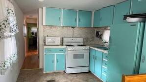 Una cocina pequeña con armarios color turquesa, una estufa blanca y un microondas.