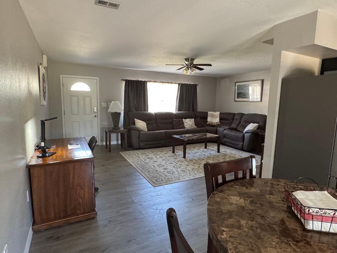 A living room with a sofa set, a coffee table, a dining table, and a desk.