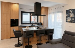 A modern kitchen with a built-in oven, a window, and a dining area with a table and four chairs. - 1 bedroom awesome apartment in Privlaka (Privlaka)