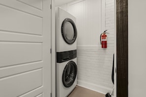 Un lavadero con dos lavadoras apiladas y un extintor colgado en la pared.