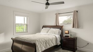 A bedroom with a bed, a nightstand, a ceiling fan, and a window with curtains. - Farm Views | 10min to Sight & Sound (Ronks)